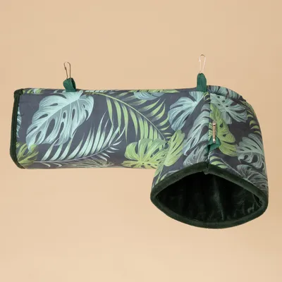 Túnel de tela con estampado de hojas tropicales, borde verde oscuro y forro interior suave. Se ven dos ganchos para fijación.