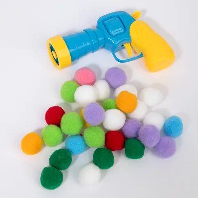 Spielzeug-Pistole in Blau und Gelb mit bunten Filzbällen in verschiedenen Farben wie Grün, Rot, Weiß, Lila und Blau. Geeignet für interaktives Spielen.