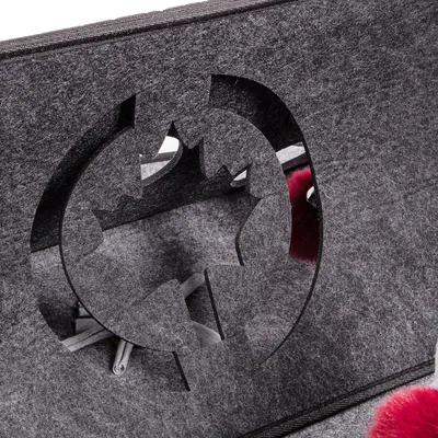 Grey felt surface with cut-out cat motif and red plush detail in the background.