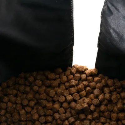 Felnyitott tápzsák barna száraztáp-pelletekkel, felülnézetből. Felnyitott tápzsák barna száraztáp-pelletekkel, felülnézetből.