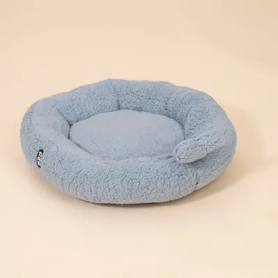 Rundes, hellblaues Bett aus weichem Plüschstoff mit erhöhtem Rand und kleinem Stoffetikett mit der Aufschrift 'Trixie'.