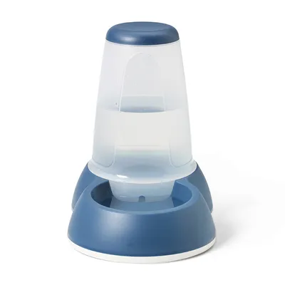 Dispenser per acqua in plastica trasparente e blu con serbatoio verticale e ciotola integrata alla base, adatto per pet. Nessun marchio o testo visibile.