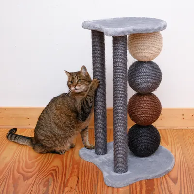 Cat tree with grey cover, three sisal posts and four balls in natural, grey, brown and black. Cat uses one post for scratching.