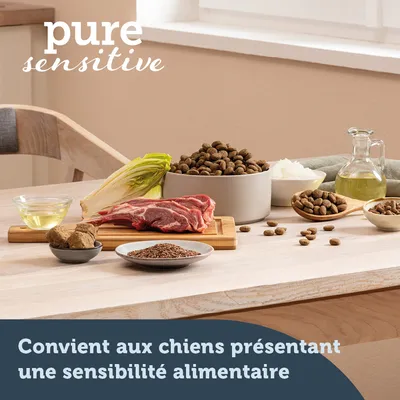 pure sensitive. Convient aux chiens présentant une sensibilité alimentaire. Ingrédients visibles : viande crue, endive, huile, croquettes, riz, graines, morceaux bruns.