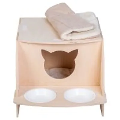 Casetta per gatti in tessuto beige con ingresso a forma di testa di gatto, due ciotole bianche integrate e coperta piegata sopra.