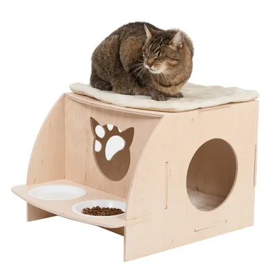 Kat på træhule med blød pude, udskåret poteform foran, to hvide skåle hvoraf én med tørfoder, rund indgang i siden. Alt synligt tilbehør inkluderet.