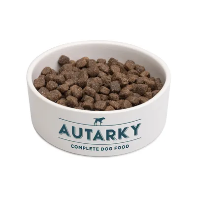 Bowl filled with Autarky complete dog food kibble, showing the product's appearance and branding.