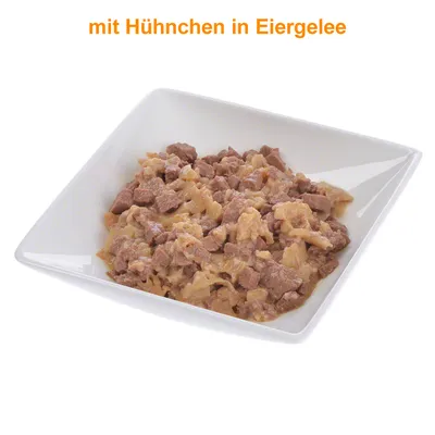 Stukjes vlees in saus geserveerd in een wit vierkant bakje, met zichtbare tekst: mit Huhnchen in Eiergelee (Duits).