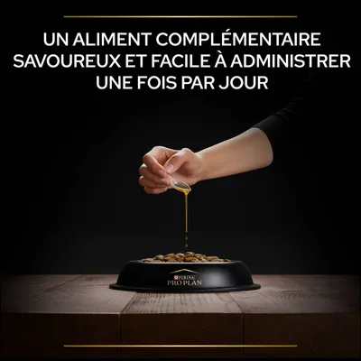 Main versant un liquide sur des croquettes dans une gamelle Purina Pro Plan. Texte : Un aliment complémentaire savoureux et facile à administrer une fois par jour.