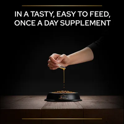 Hand pouring liquid supplement onto kibble in a PURINA PRO PLAN bowl. Text: IN A TASTY, EASY TO FEED, ONCE A DAY SUPPLEMENT.