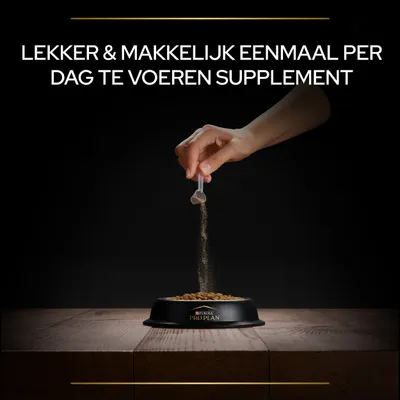 Hand strooit poeder uit een maatschepje over brokken in een Purina Pro Plan voerbak. Tekst: Lekker & makkelijk eenmaal per dag te voeren supplement.