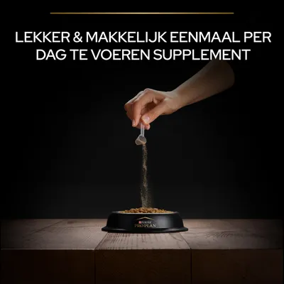 Hand strooit poeder uit een maatschepje over brokken in een Purina Pro Plan voerbak. Tekst: Lekker & makkelijk eenmaal per dag te voeren supplement.