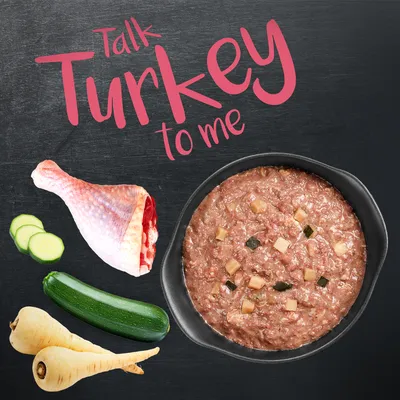Bol de pâtée avec morceaux, cuisse de dinde crue, courgette, panais et texte anglais 'Talk Turkey to me' en haut de l’image.