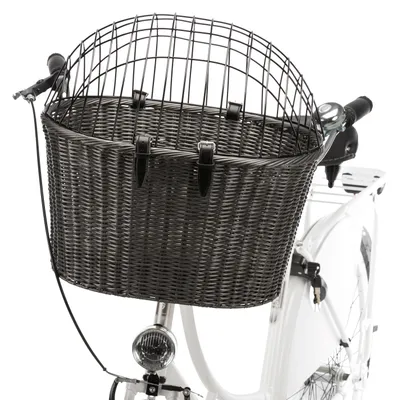 Sort cykelkurv af flettet materiale med metalgitterlåg, fastgjort til styret på en hvid cykel.