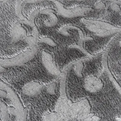 Close-up van een grijze stof met bloemmotieven en fluweelachtige textuur.