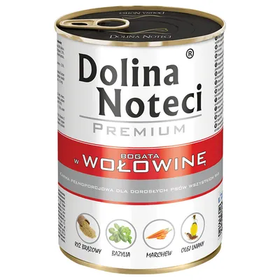 Conservă Dolina Noteci Premium, bogată în vită. Text vizibil: orez brun, busuioc, morcov, ulei de in. Pentru câini adulți. Ambalaj cu capac metalic.