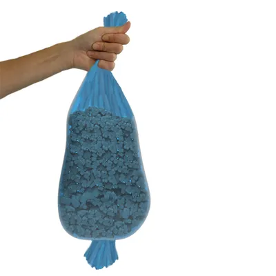 Mão segura um saco azul com pedaços de granulado azul, provavelmente embalagem para areia ou material semelhante.