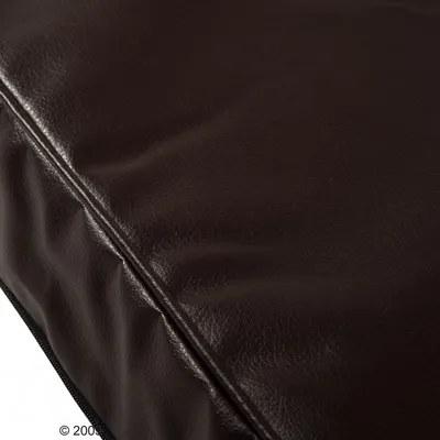 Gros plan sur une housse de coussin ou matelas en similicuir marron foncé avec fermeture éclair visible sur le côté.