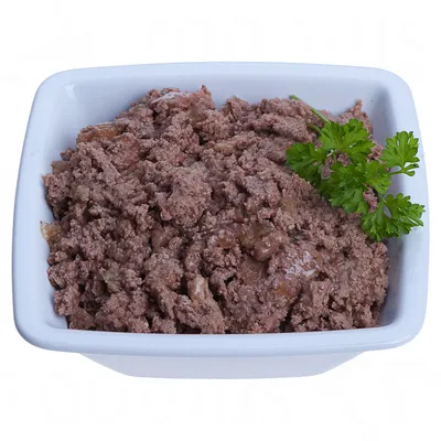 Skleda z vlažno, rjavo mesno mešanico in svežim peteršiljem kot okras.