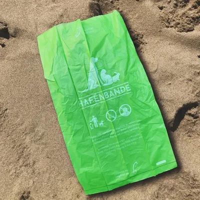 Grøn hundepose med Hafenbande-logo, advarsel om sikker bortskaffelse og miljøvenlige symboler. Tekst: Ikke egnet til børn, ikke legetøj.