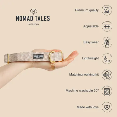 Nomad Tales München collar held in hand, beige fabric with gold metal parts. Visible text: Premium quality, Adjustable, Easy wear, Lightweight, Matching walking kit, Machine washable 30°, Made with love.