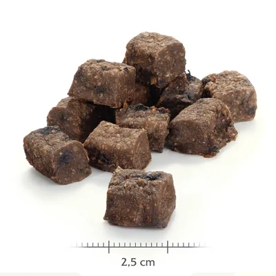Bruine brokjes hondensnack, stapel van blokjes met zichtbare structuur. Maatindicatie: 2,5 cm per stuk.