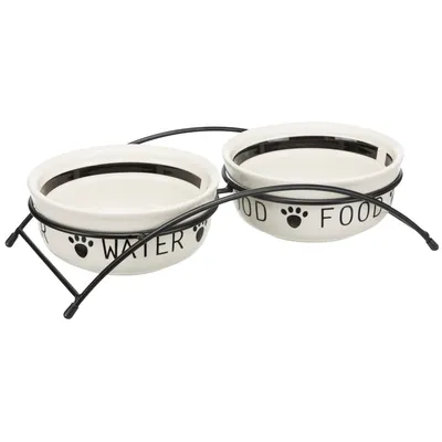 Dubbelskål i keramik med svart metallställ. Text: 'Water' och 'Food' med tassavtrycksdesign.