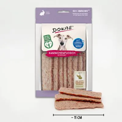 DOKAS Kaninchenfleisch gedroogd, verpakking met stroken konijnenvlees, zichtbaar label '100% Kaninchen', lengte ca. 11 cm, afbeelding hond op de verpakking.