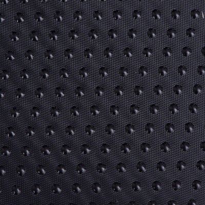 Detalle de superficie de tela negra con puntos antideslizantes en relieve, material sintético visible en primer plano.