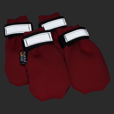 Vier rote Pfotenschuhe mit Klettverschluss und weißem Streifen, Markenetikett 'rukka' sichtbar.