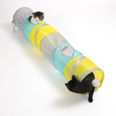 Tunnel de jeu pour chat en tissu jaune, bleu et gris, avec deux ouvertures latérales et une balle suspendue, un chat noir et un chat blanc à l'intérieur.