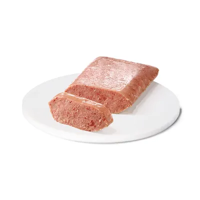 Skivad bit av rosa patéliknande våtfoder på vit tallrik, ingen synlig förpackning eller märkning.