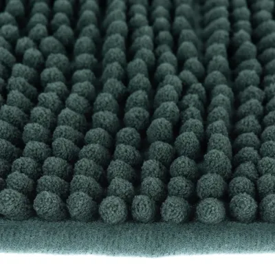 Close-up van een donkergroene mat met een zachte, gestructureerde oppervlakte van kleine stoffen nopjes.