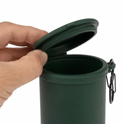 Boîte cylindrique verte en plastique avec couvercle ouvert, tenue par une main, munie d’un mousqueton noir sur le côté.