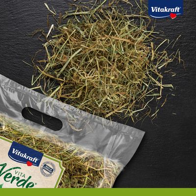 Vitakraft Vita Verde сено в прозрачной упаковке с рассыпным сеном рядом. Знак: Made in Germany, натуральное качество.