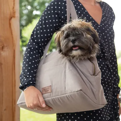 Tragetasche in Beige mit Hund, geeignet für den Transport kleiner Haustiere. Detailansicht der Tasche mit Reissverschluss und Markenetikett 'Designed by Lotte'.