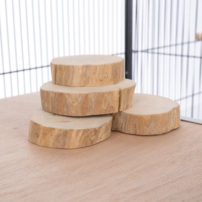 Quattro dischi di legno naturale impilati su una superficie di legno, con una griglia metallica sullo sfondo.