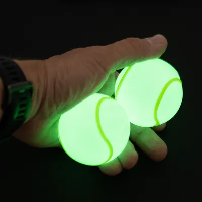 Zwei leuchtende Tennisbälle in einer Hand, geeignet für Spiele im Dunkeln.