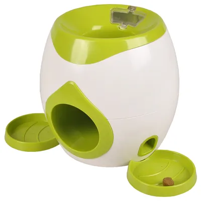 Jouet distributeur de friandises pour animaux, en plastique blanc et vert, avec deux ouvertures circulaires et deux plateaux amovibles, une croquette visible dans un plateau.