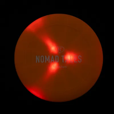 Nomad Tales München. Disco arancione con accenti rossi vivaci e logo NT visibile.