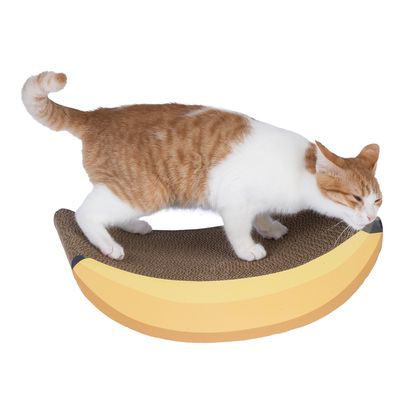 Chat roux et blanc sur un griffoir en carton en forme de banane. Le matériau visible est du carton ondulé, la base a un motif jaune rappelant une banane.