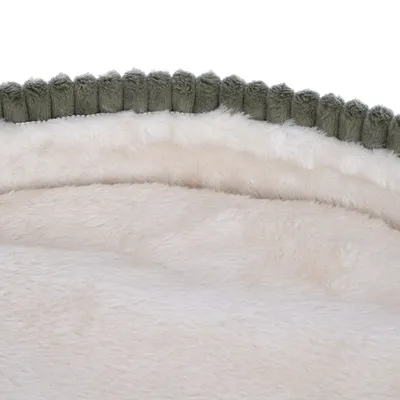 Close-up de material peluche macio de cor creme com detalhe de rebordo verde.