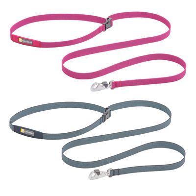 Henkilö oranssi reppu selässä juoksee koiran kanssa ylämäkeen hihnassa ulkoilupolulla. Koiralla on sininen valjas ja kaulapanta.