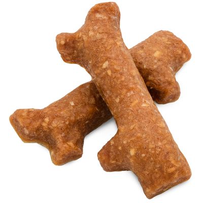 Snack per cani marroni a forma di osso in materiale pressato, con texture granulosa visibile.