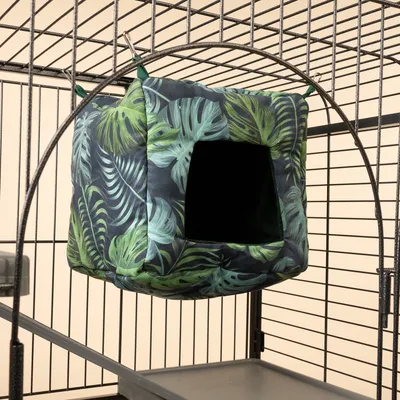 Hangende kubusgrot met tropisch bladmotief, bevestigd aan metalen kooi met clips. Geschikt als schuilplaats voor kleine dieren.