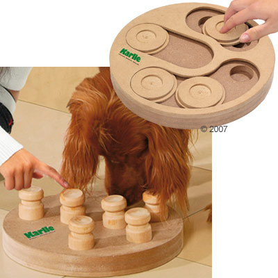 Karlie Intelligenzspielzeug aus Holz mit beweglichen Elementen. Hund interagiert mit dem Spielzeug, während eine Hand die Funktion demonstriert. Karlie Intelligenzspielzeug aus Holz mit beweglichen Elementen. Hund interagiert mit dem Spielzeug, während eine Hand die Funktion demonstriert.