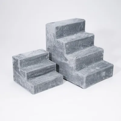 Zwei graue Treppenstufen aus weichem Material in unterschiedlichen Größen, nebeneinander aufgestellt. Zwei graue Treppenstufen aus weichem Material in unterschiedlichen Größen, nebeneinander aufgestellt.