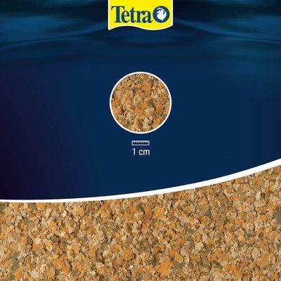 Tetra vlokkenvoer, detailopname van de vlokkenstructuur met schaal: 1 cm. Merknaam Tetra zichtbaar bovenaan.