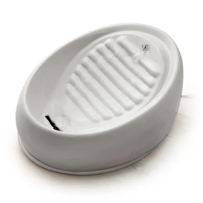 Fontaine à eau en céramique blanche avec surface ondulée et petit jet d’eau, vue de trois quarts sur fond blanc. Aucun logo ou texte visible.