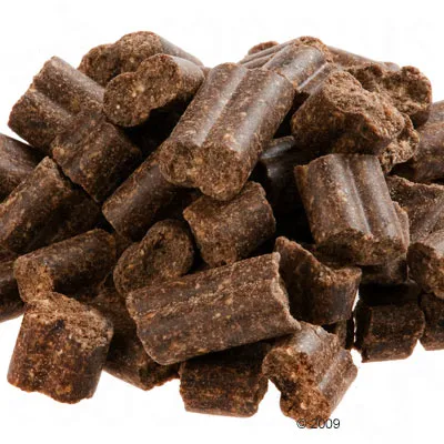 Bruine, langwerpige hondensnacks in stukjes, zichtbaar grove textuur.